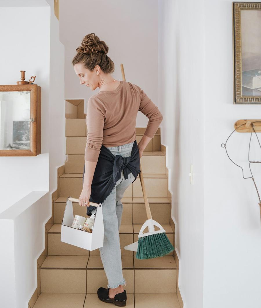 Cleaner carrying equipment up an indoor staircase