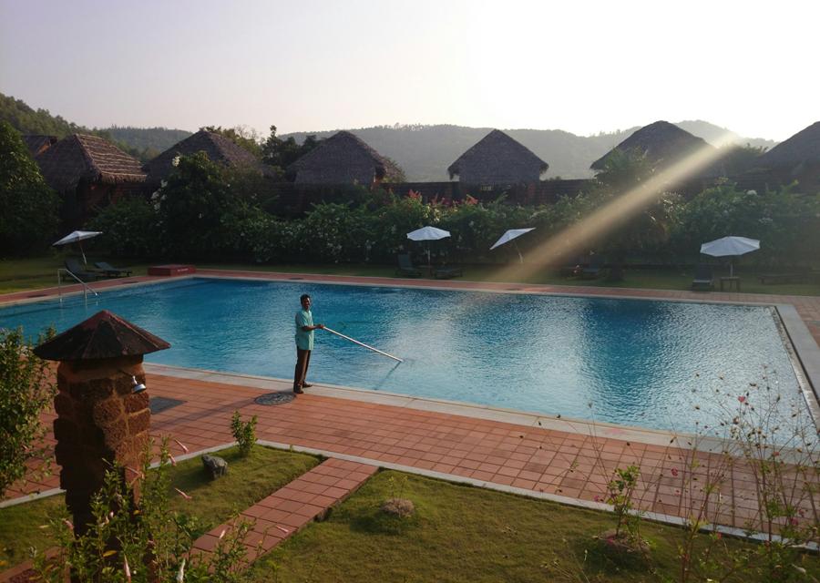 Technician cleaning a pool in the late afternoon